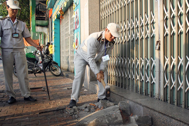 Lực lượng chức năng đem theo xà beng, búa đã đập bỏ những bậc cấp do các hộ dân, công ty, ngân hàng tự ý xây dựng trên vỉa hè.