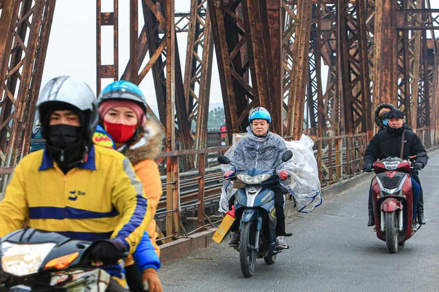 Trên cầu Long Biên một người mặc áo mưa để chắn gió rét.