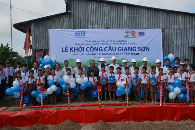 Đại diện của Thuốc nhỏ mắt Osla, HAGL, xã Bình Giang, xã Bình Sơn cùng các em học sinh thực hiện nghi thức khởi công xây dựng cầu Giang Sơn. Ảnh: Quốc Bảo