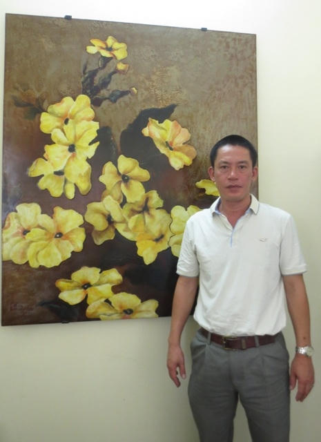 Anh Đỗ Hữu Triết bên bức Hoàng hoa - là một sản phẩm pháp lam được thiết kế theo kiểu sơn mài. (Ảnh Thanh Nhàn)