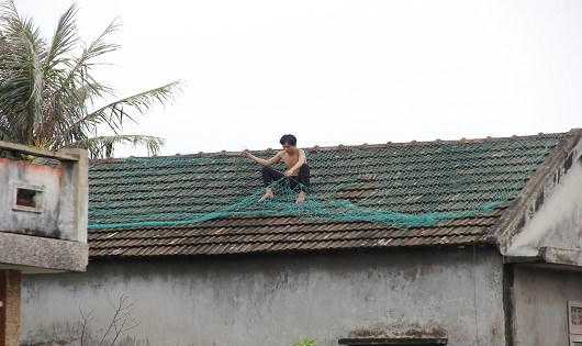 Một người dân chằng lưới bảo vệ mái nhà.