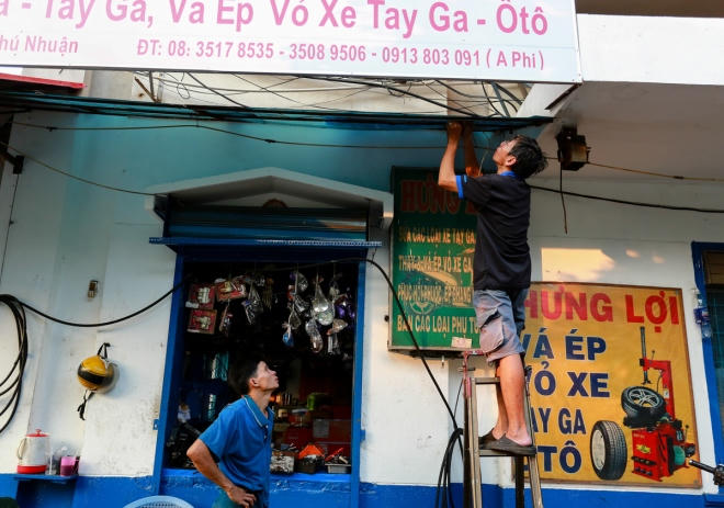 Anh Phi, chủ tiệm xe máy, tháo dỡ tấm phông bạt lấn chiếm không gian vỉa hè. Từ ngày 25/2, trước những đợt kiểm tra, xử phạt thường xuyên nhằm "đòi vỉa hè" cho người đi bộ của quận 1, nhiều hộ dân ở quận này cũng đã chủ động thuê nhân công đập bỏ các bậc tam cấp lấn chiếm vỉa hè trước khi lực lượng chức năng đến xử lý.