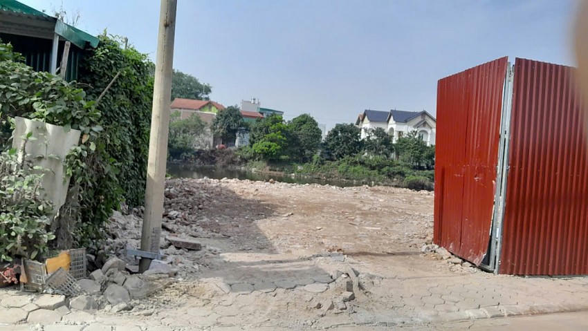 Bên ngoài bờ đầm được quây bằng hàng rào tôn và để một cánh cổng cho xe đổ phế thải xây dựng ra vào. Vỉa hè đi lại của người dân bị những chiếc xe tải cày nát.