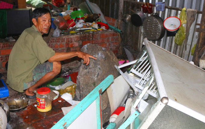 Ông Nguyễn Văn Dương, và tảng đá lớn hơn 2 tấn rơi xuống nhà khi gia đình ông ăn cơm.