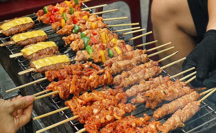Hàng xiên nướng bẩn tồn tại phổ biến tại các khu vực đường phố đông người như vỉa hè cổng trường, chợ cóc, lề đường… tiềm ẩn nguy cơ ngộ độc thực phẩm, nhiễm khuẩn và tích tụ độc tố lâu dài cho người tiêu dùng. (Ảnh minh họa: laodong.vn)