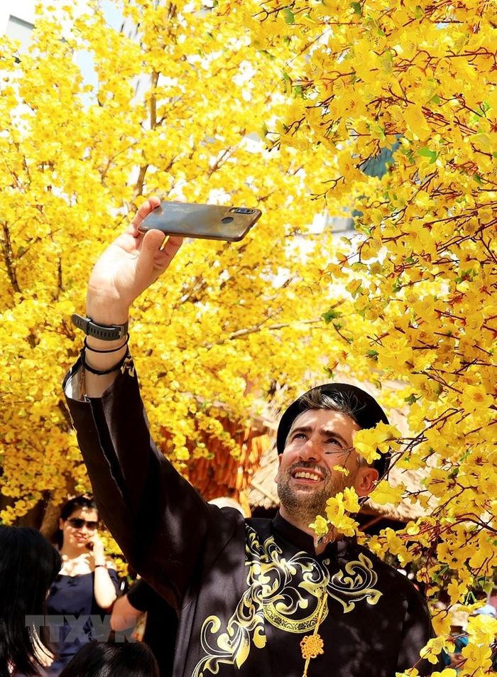 Khách quốc tế trải nghiệm không gian mai vàng đất phương Nam ngày 29 Tết. (Ảnh: Hồng Đạt/TTXVN)