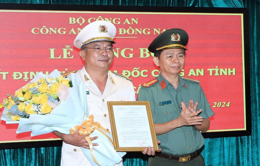 Đại tá Trần Tiến Đạt, Phó Giám đốc Công an tỉnh trao quyết định và tặng hoa chúc mừng Trung tá Lê Minh Tuấn.