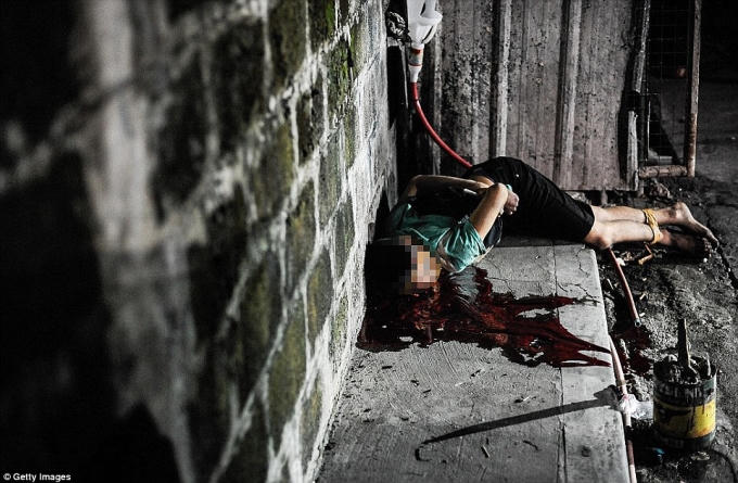 Cảnh sát chụp ảnh 1 nạn nhân tình nghi là tội phạm ma túy bị bắn chết trong tư thế 2 chân tay bị chói và quấn băng kín đầu trên đường phố Manila. (Ảnh: Daily Mail)