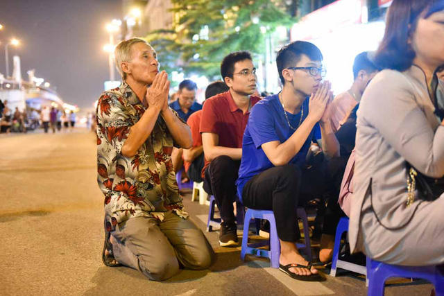 Người đàn ông quỳ dưới lòng đường, chắp tay hướng về phía chùa hành lễ.