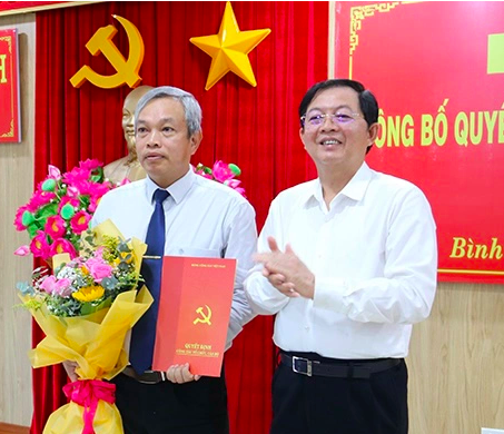 Bí thư Tỉnh ủy Bình Định Hồ Quốc Dũng trao Quyết định của Ban Bí thư, tặng hoa chúc mừng ông Đặng Vĩnh Sơn. Ảnh: BBĐ.