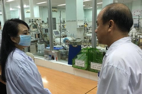 Bộ trưởng Tiến và BS Nguyễn Hữu Lân tại khoa chăm sóc đặc biệt BV Pham Ngọc Thạch. Người thăm chỉ được đứng bên ngoài nhìn qua cửa kính.
