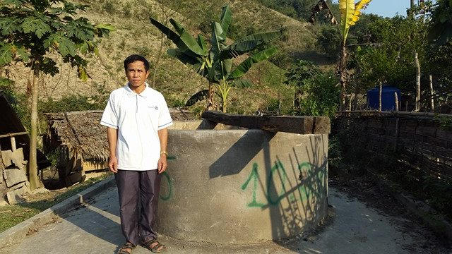 Ông Lang Văn Thành bên cạnh giếng nước được xây dựng nhưng nguồn nước không sử dụng được.