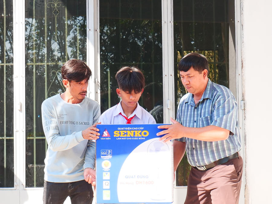 Ông Võ Thanh Hải - Phó Bí thư Thường trực Đảng ủy xã Thanh Phú, TX. Bình Long (bìa phải) tặng quà cho gia đình em Nguyễn Huỳnh Quốc Bảo tại lễ bàn giao Nhà Khăn quàng đỏ.