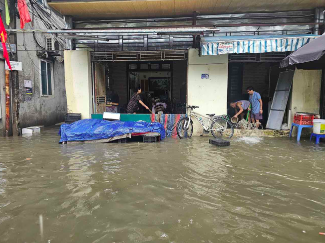 Mưa lớn kéo dài khiến cho nhiều nhà dân có nền thấp phải dùng ván gỗ để ngăn nước và tát nước cho đỡ hỏng đồ đạc trong nhà.