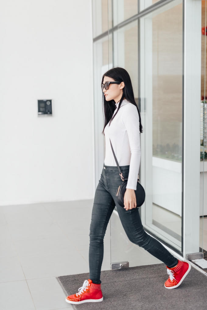 Dù là tín đồ thời trang, chân dài không quá cầu kỳ chọn trang phục đi làm, cô diện áo thun ôm dài tay, quần jean cùng giày sneaker năng động, khoẻ khoắn. (Photo: Nghĩa Ngô)