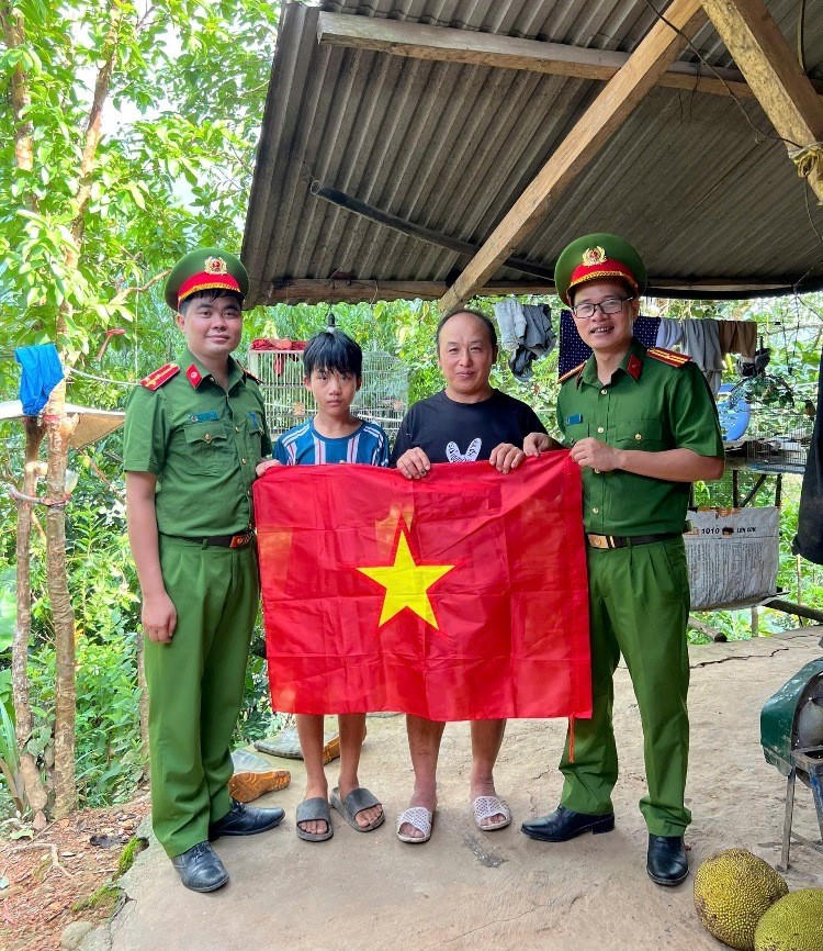 Thiếu tá Vũ Văn Chính (ngoài cùng bên phải) gửi tặng đến bà con xã Pa Tần những là cờ Tổ quốc mới.