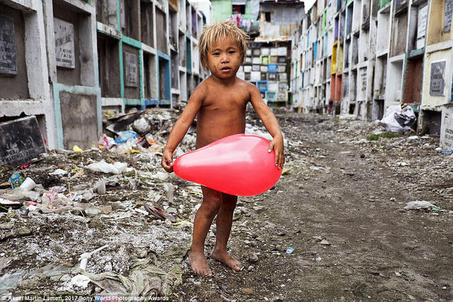 Bức ảnh được chụp tại một nghĩa trang ở Manila, Philippines, tại đây, có những người vô gia cư sinh sống, cậu bé này là con của một gia đình nghèo sinh sống tại đây.