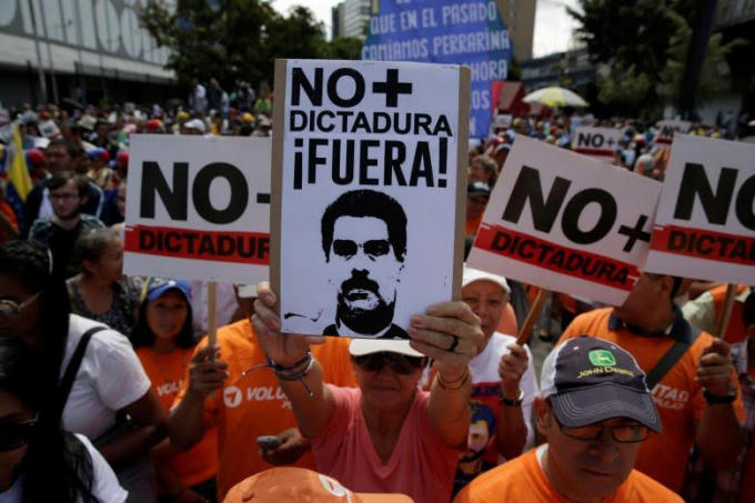 Một người ủng hộ phe đối lập cầm bảng với hình ảnh Tổng thống Nicolas Maduro và dòng chữ: “Không có chỗ cho chế độ độc tài”.