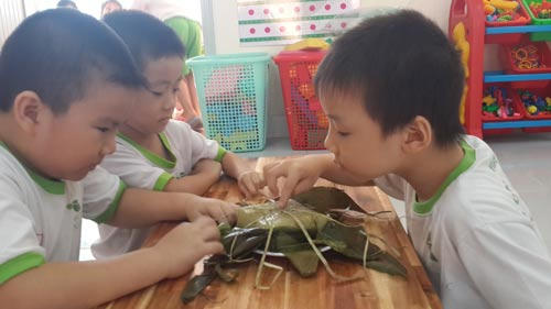 Học sinh một trường mầm non làm quen với việc bóc bánh chưng nhân dịp Tết sắp đến Ảnh: BẢO LÂM