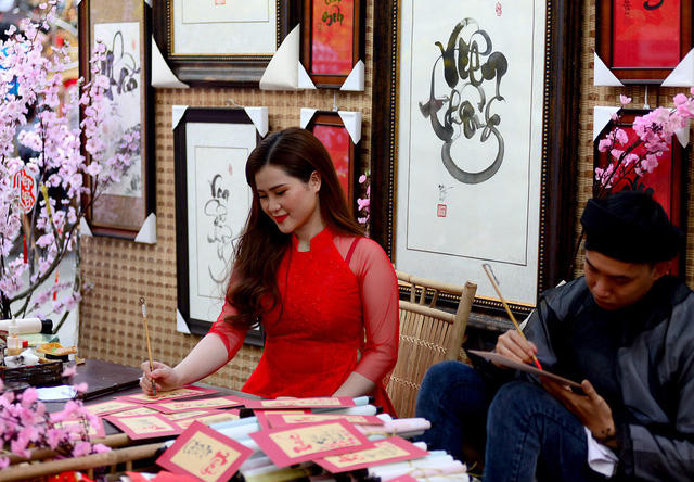 Tạo dáng bên bàn viết thư pháp.