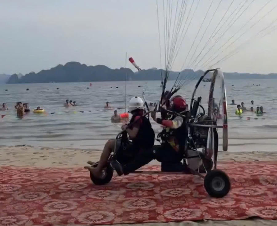 Chiếc dù lượn hai chỗ, gắn động cơ cất cánh tại trên bãi biển có rất nhiều du khách.