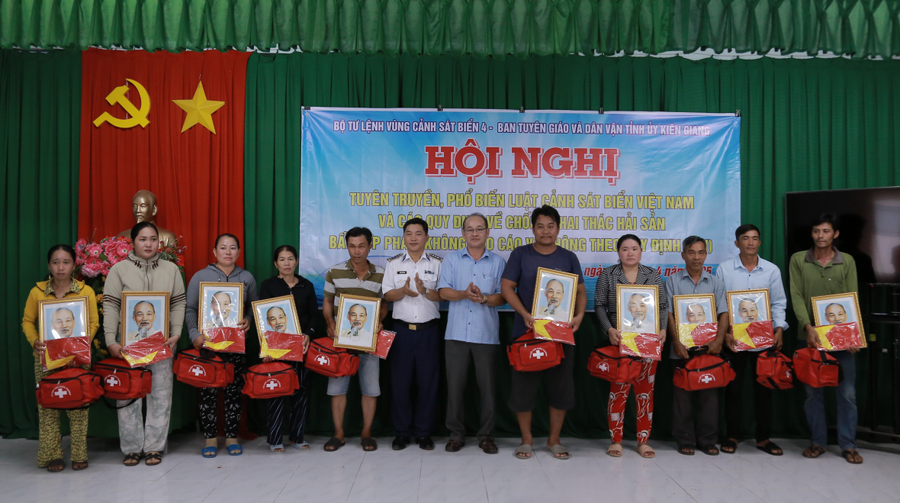 Đại diện Bộ Tư lệnh Vùng Cảnh sát biển 4 và đại diện lãnh đạo địa phương tặng Cờ Tổ quốc, ảnh Bác Hồ và túi thuốc y tế cho ngư dân trên địa bàn xã Đông Hưng A, huyện An Minh.