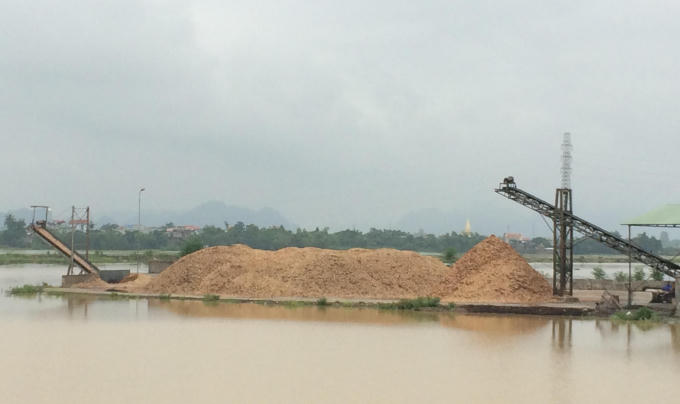 Bãi tập kết dăm gỗ lấn chiếm ra sông Hoàng Long gây ảnh hưởng đến dòng chảy. Ảnh: Nguyệt Chi