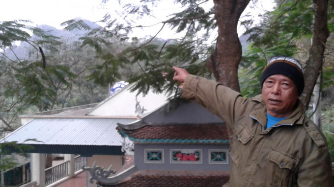 Ông Tống Văn Hái đứng từ trên cao chỉ về ngọn núi có chiếc chum vàng cổ tích. Ảnh: Nguyệt Chi