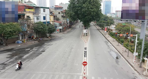 Tại ngã tư đường Láng – Nguyễn Chí Thanh, hai phụ nữ đi xe gắn máy từ từ giảm tốc độ dừng đèn đỏ dù chiều đường giao cắt không có phương tiện đi qua.