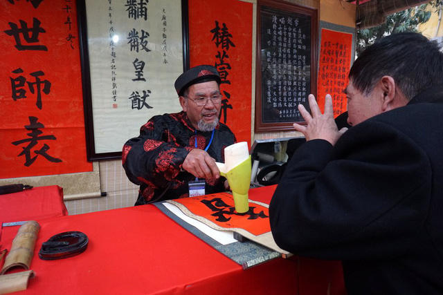 Ông đồ và khách cùng trao đổi trong khi viết chữ.