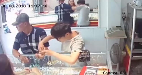 người nhà chủ tiệm vàng đang loay hoay tháo chiếc lắc tay