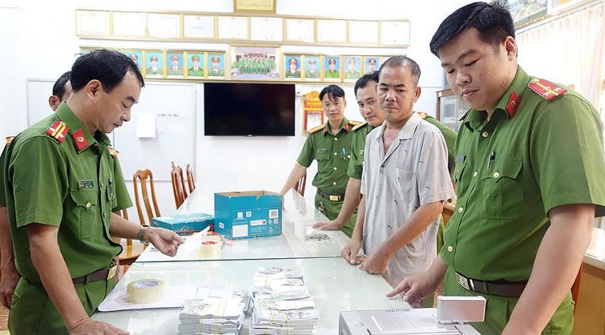 Một trong 3 đối tượng trong đường dây vận chuyển trái phép tiền tệ qua biên giới cùng số tang vật bị lực lượng chức năng thu giữ. Ảnh: BCA.