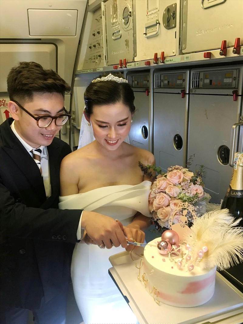 Cặp đôi cắt bánh cưới trên máy bay. Ảnh: VNA