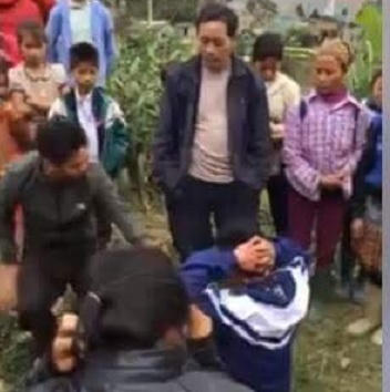 Nam thanh niên mặc đồng phục học sinh “cướp vợ” phải quỳ xuống nhấc tay lên đầu để xin lỗi người đàn ôn người Mông do bắt nhầm vự của anh ta. Ảnh cắt từ clip.