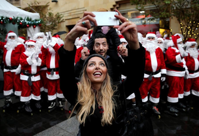 Một cuộc diễu hành truyền thống đã được tổ chức tại Beirut (Lebanon) nhân lễ Giáng sinh sắp đến gần. Một gia đình người Libanon chụp ảnh trên con phố ngập tràn sắc màu trắng - đỏ của những ông già Noel.(Ảnh: AP)