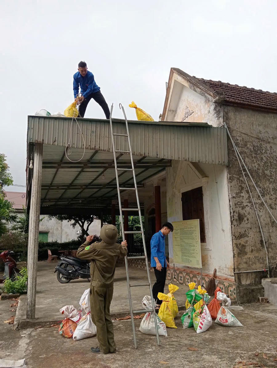 Thanh niên hỗ trợ người dân che chắn mái nhà.