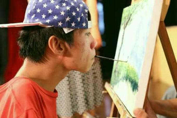 Chàng trai Việt Lê Minh Châu vẽ tranh bằng cách ngậm bút trong miệng. Ảnh: Internet