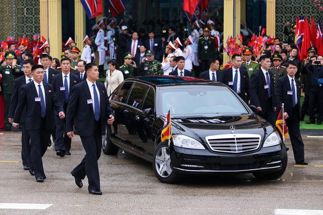 Siêu xe bắt đầu lăn bánh chậm, đội vệ sĩ di chuyển xung quanh xe ở khoảng cách chính xác và nhìn về các hướng xung quanh.