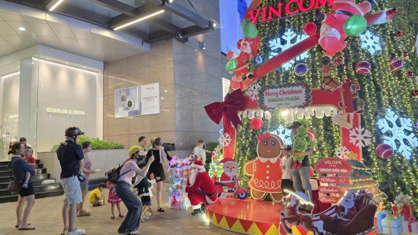 Tại trung tâm thương mại Vincom, nhiều phụ huynh và trẻ em xếp hàng chờ chụp ảnh bên cây thông Noel.
