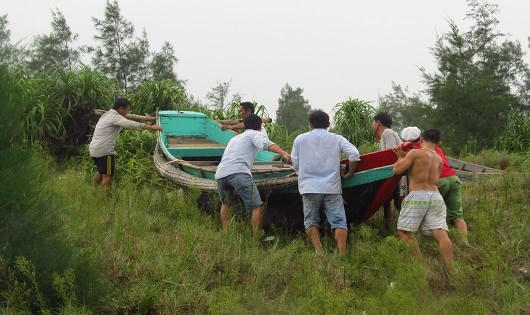 Tàu cá được ngư dân hợp sức đưa lên bờ.