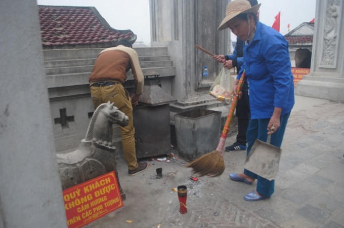 Nhân viên vệ sinh quét dọn khuôn viên đền Cờn. (Ảnh Duy Ngợi)