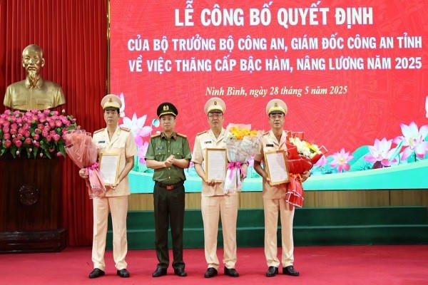 Đại tá Đinh Việt Dũng, Giám đốc Công an tỉnh Ninh Bình trao Quyết định của Bộ trưởng Bộ Công an và tặng hoa chúc mừng các đồng chí được nâng lương và thăng cấp bậc hàm.