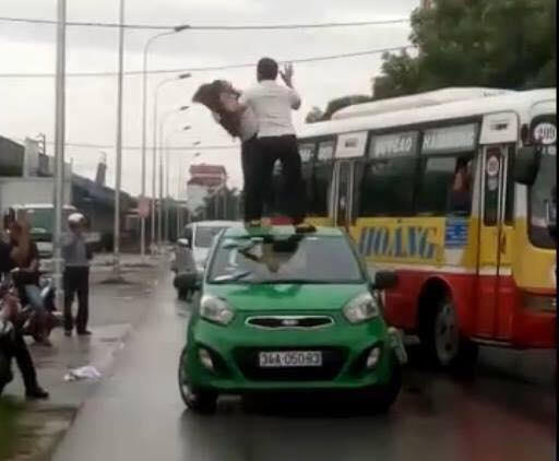 Hình ảnh người đàn ông đánh người phụ nữ trên nóc xe taxi. Ảnh cắt từ clip.