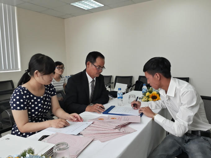 Doanh nghiệp và người mua nhà ký hợp đồng nhận sổ hồng nhà chung cư.
