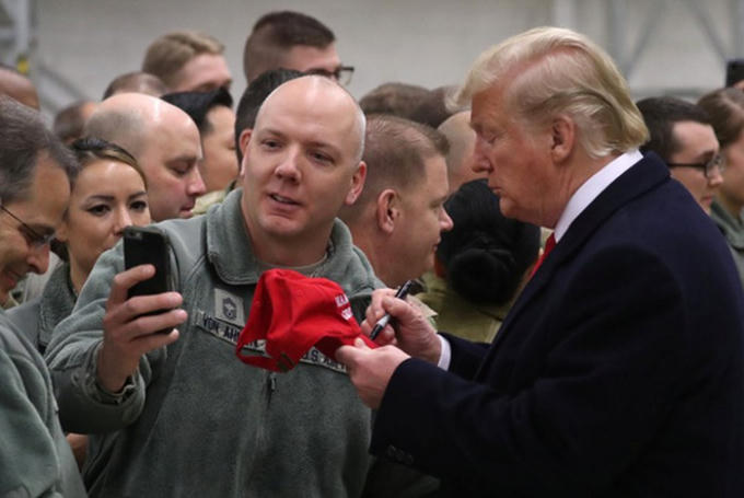 Tổng thống Donald Trump ký lên chiếc mũ có chữ “Nước Mỹ trên hết” trong chuyến thăm binh sĩ Mỹ ở Căn cứ Không quân Ramstein tại Đức Ảnh: REUTERS