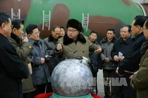 Nhà lãnh đạo Triều Tiên Kim Jong-un (giữa) trong một cuộc gặp với các nhà khoa học và kỹ thuật viên trước mô hình một phần đầu đạn hạt nhân thu nhỏ ngày 9/3. (Ảnh: Yonhap/TTXVN)