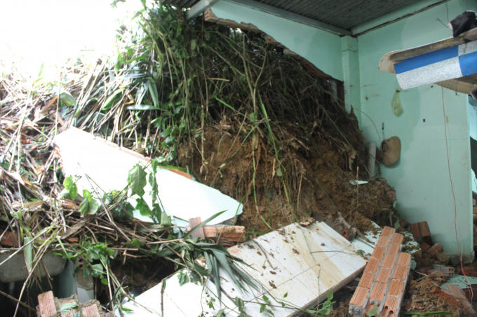 Đất đá đổ xuống làm bức tường nhà dân bị sập đổ.