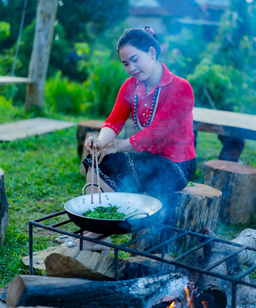 Trong trang phục truyền thống, cô gái Hrê xào rau dớn - món lạ miệng đối với nhiều du khách.