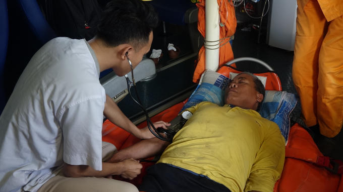 Bệnh nhân (áo vàng) bị liệt nửa người bên phải, nghi tai biến mạch máu não, nguy hiểm đến tính mạng.