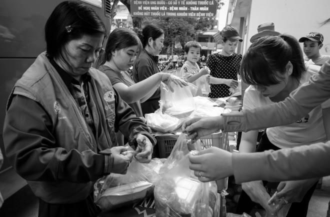 Các tình nguyện viên của Hội Chữ thập đỏ quận Bình Thạnh, Hội Chữ thập đỏ Thiện Tâm, quán cơm Nụ Cười 3 và Bệnh viện Ung bướu TP HCM tất bật chuẩn bị đồ ăn cho các bệnh nhân. Theo đại diện ban tổ chức, toàn bộ chi phí thuê xe khách và ăn uống cho bệnh nhân và người thân đều do các mạnh thường quân ủng hộ.